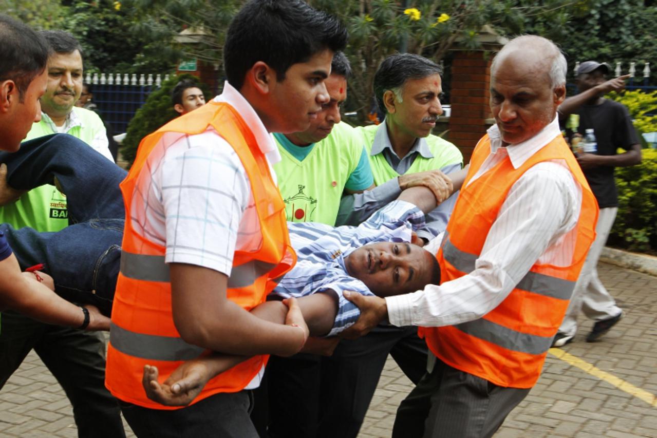 'Volunteers at the MP Shah hospital assist a man whose relative was killed in Saturday's attack at the Westgate shopping mall in Nairobi September 22, 2013. Kenyan security forces were locked in a st