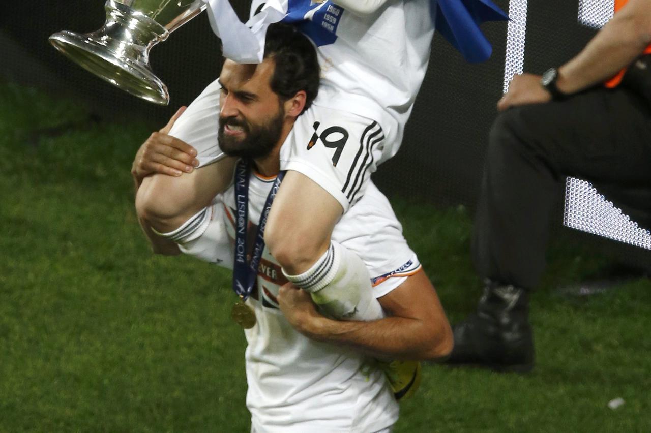 Real Madrid's Luka Modric (top) holds the trophy on top of Alvaro Arbeloa as they celebrate after defeating Atletico Madrid in their Champions League final soccer match at the Luz Stadium in Lisbon May 24, 2014.       REUTERS/Sergio Perez (PORTUGAL  - Tag