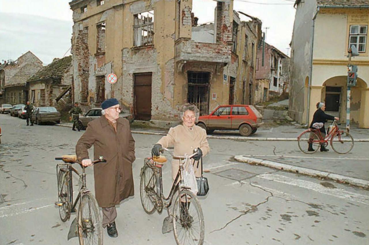 'A Croatian Serb couple pushes their bicycles 18 November downtown Vukovar in Croatia's disputed eastern Slavonia region. Croatians in eastern Slavonia today commemorated the 4th anniversary of the f