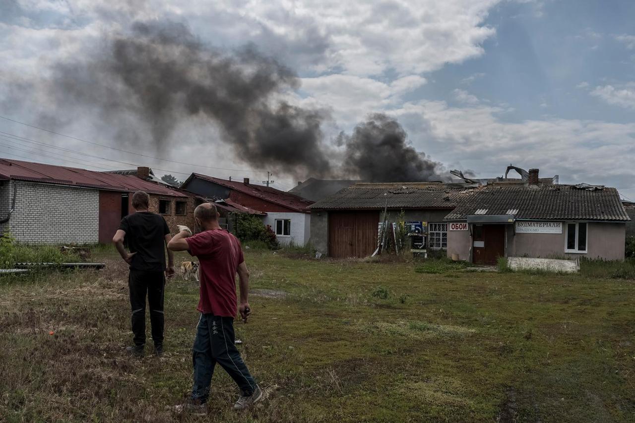 Local residents walk while smoke rises after shelling near the Ukraine-Russia border in the town of Vovchansk