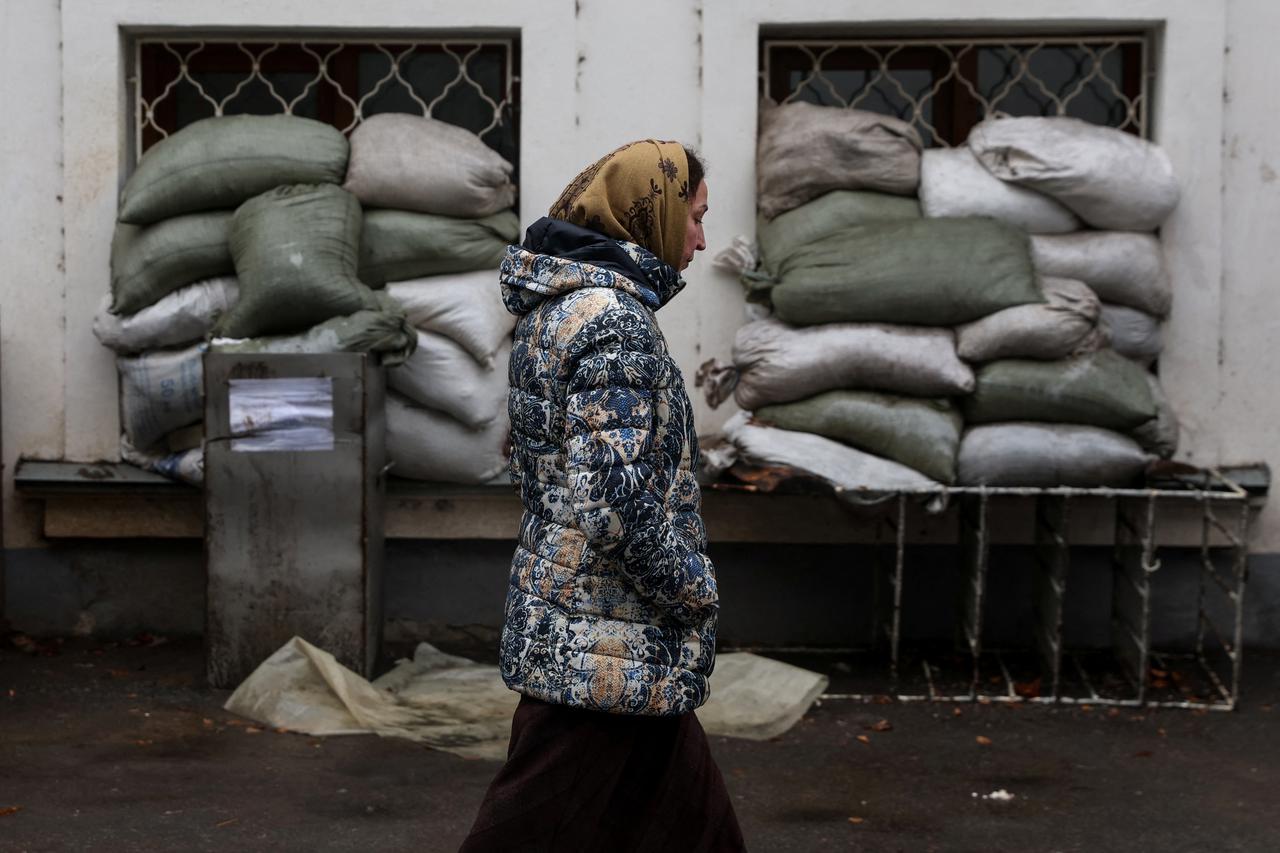 A woman who sought refuge at the Sviatohirsk Cave Monastery walks by sand bags