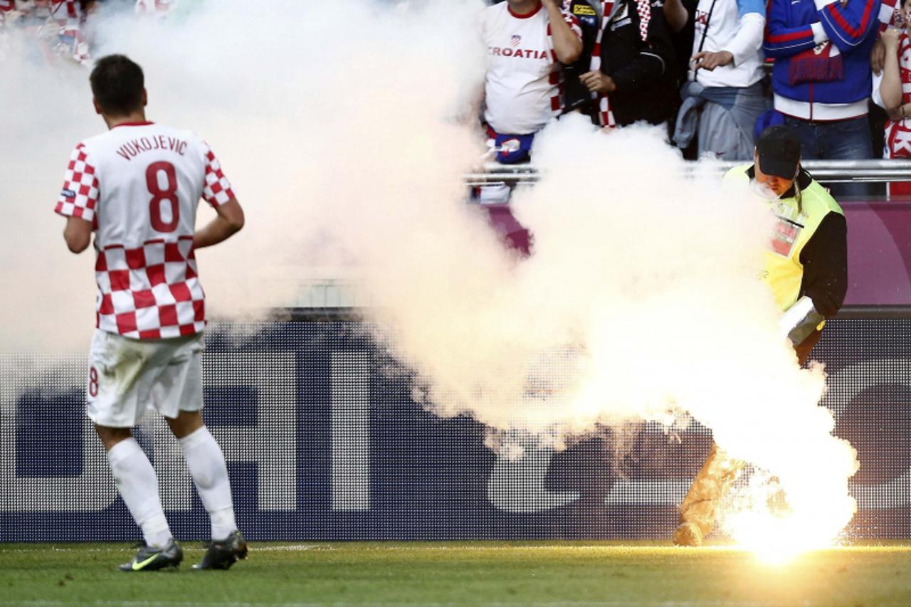 'A steward removes a flare from the pitch next to Croatia\'s Ognjen Vukojevic during their Group C Euro 2012 soccer match against Italy at the city stadium in Poznan June 14, 2012.         REUTERS/Dom