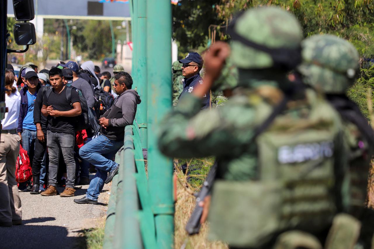 Mexican authorities keep watch as migrants descend from a tractor-trailer in Chiapa de Corzo