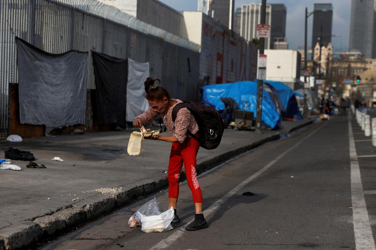 A woman eats food she found in the street in the Skid Row neighborhood of downtown Los Angeles, California