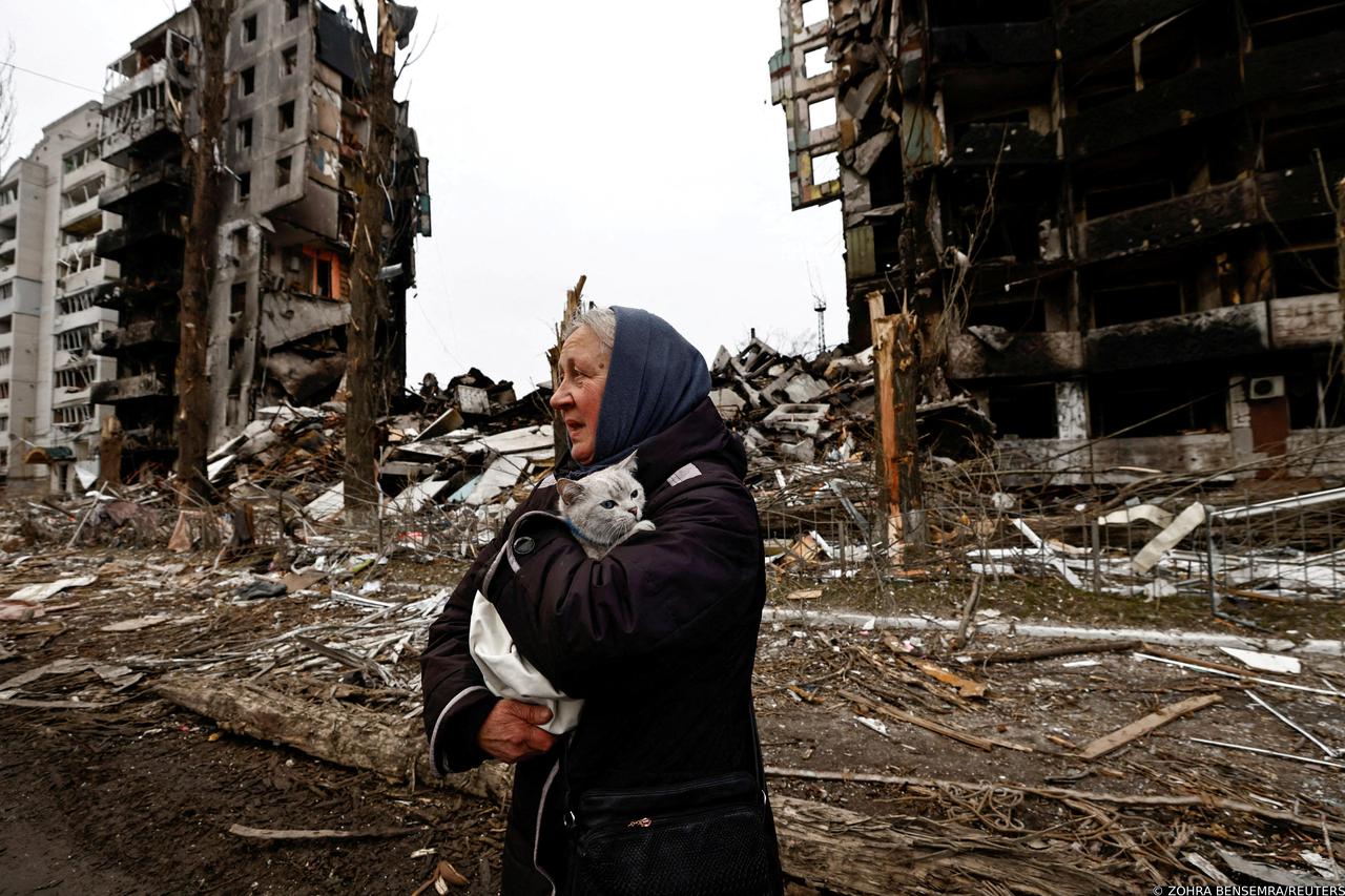 FILE PHOTO: A woman carries her cat as she walks past buildings that were destroyed by Russian shelling