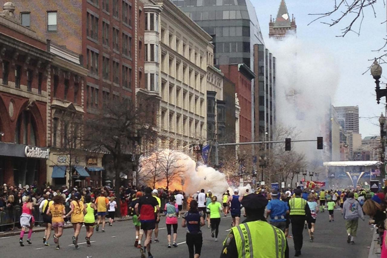 'Runners continue to run towards the finish line of the Boston Marathon as an explosion erupts near the finish line of the race in this photo exclusively licensed to Reuters by photographer Dan Lampar