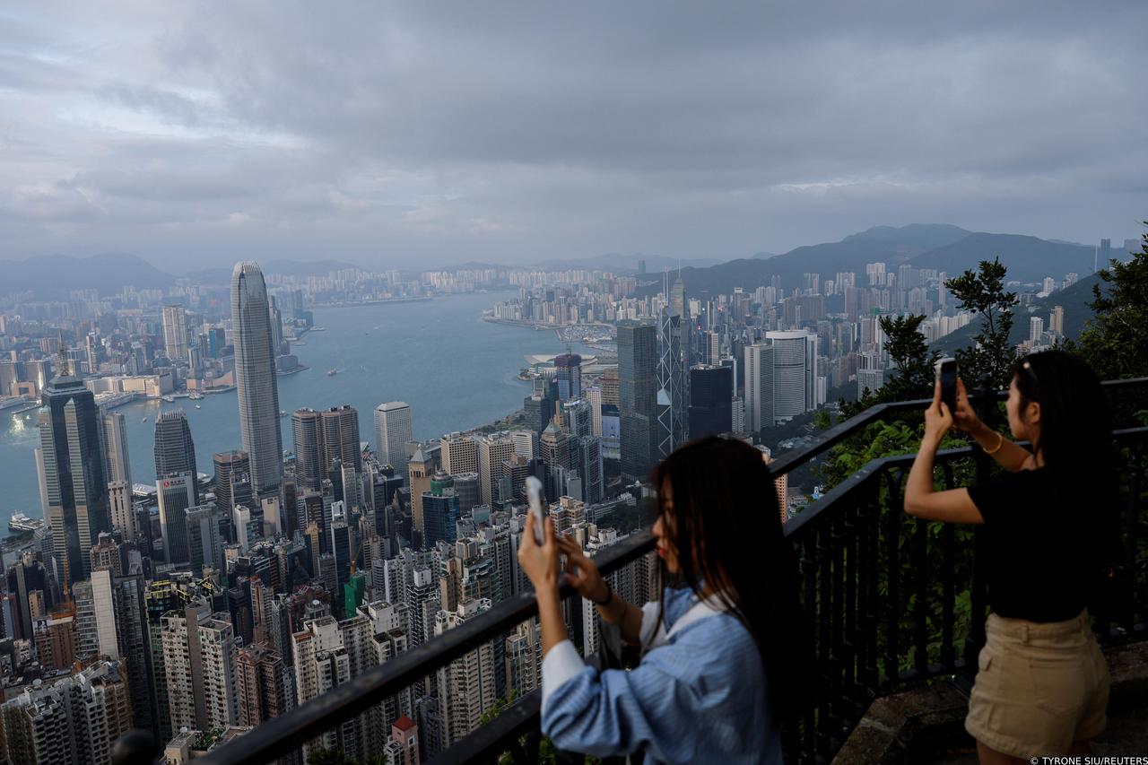 Tourists take photos in front of the financial Central district and Victoria Harbour in Hong Kong