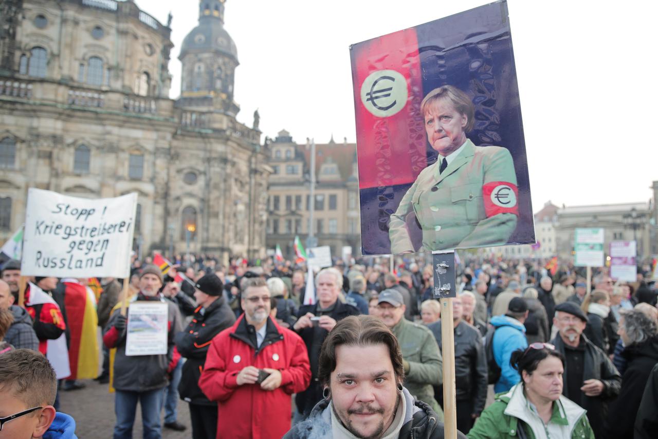 A demonstrator's sign shows German Chancellor Merkel in uniform wearing a Euro armband in Dresden, Germany, 19 October 2015. One year ago, Pegida (Patriotic Europeans against the Islamification of the West), demonstrated on the streets for the first time.