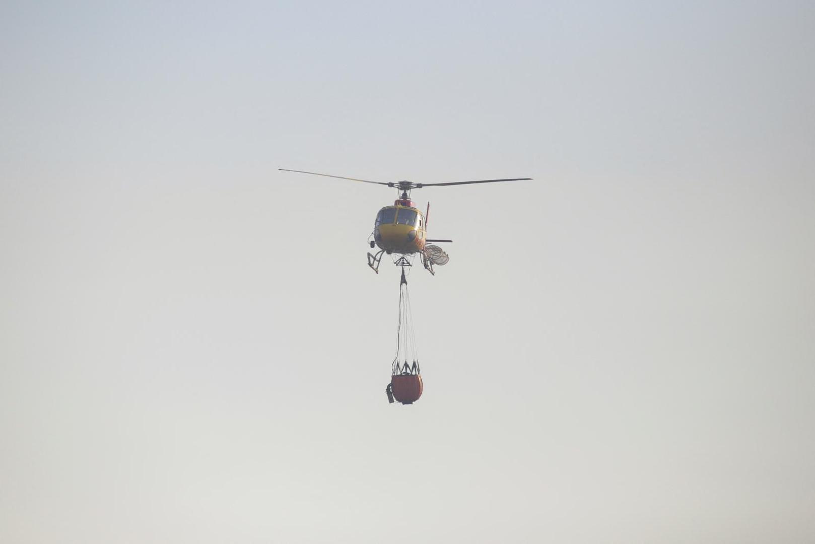 A helicopter with a water bucket flies over a burnt area to extinguish the fire during the spread of wildfires in Vina del Mar, Chile February 3, 2024. REUTERS/Sofia Yanjari Photo: SOFIA YANJARI/REUTERS