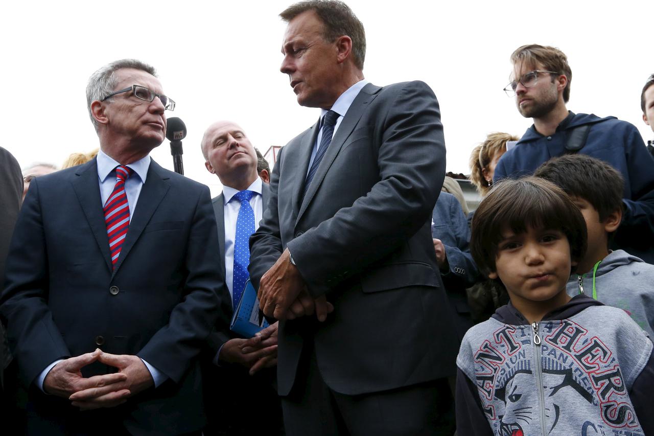 German Interior Minister Thomas de Maiziere (L) and parliamentary faction leader of Germany's Social Democratic Party (SPD) Thomas Oppermann (C) speak during a visit to Friedland refugee camp, housing about 3,000 refugees, in Friedland, Germany, August 25