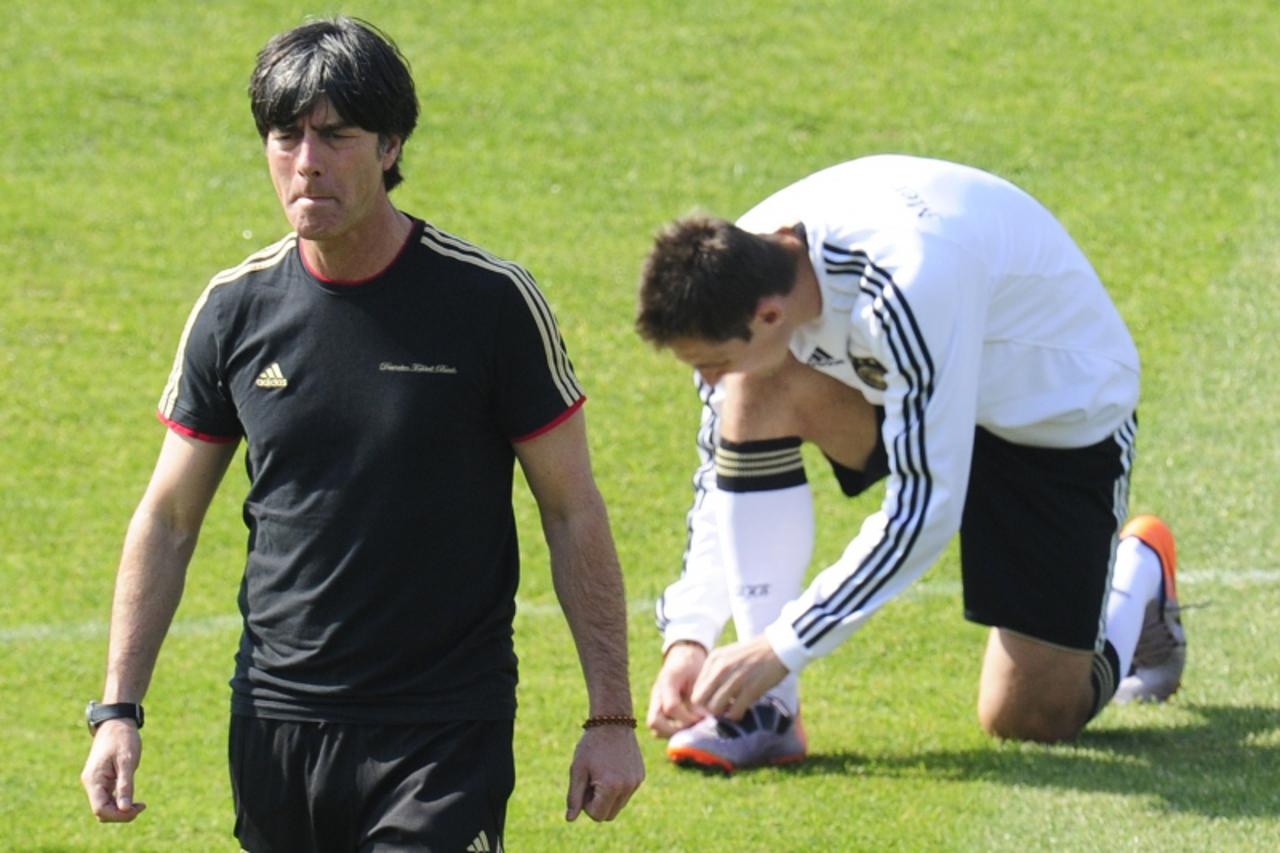 'Germany\'s coach Joachim Loew (L) walks past Germany\'s striker Miroslav Klose fixing his boots during a training session at the Super stadium in Atteridgeville near Pretoria  July 1, 2010 two days b