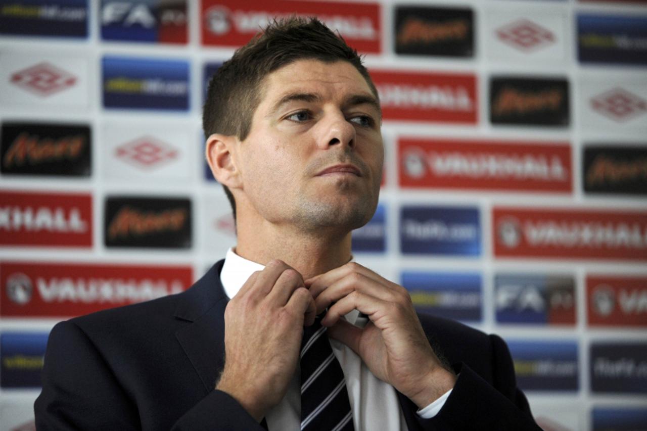 'England\'s national team player Steven Gerrard adjusts his tie as he attends a press conference during the EURO 2012 soccer tournament in Krakow June 25, 2012.  REUTERS/Pawel Ulatowski (POLAND  - Tag