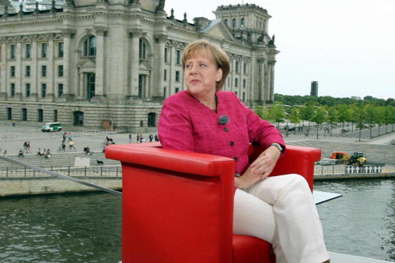 'German Chancellor Angela Merkel has taken her seat to give her traditional summer interview to German public tv chain ARD on July 17, 2011 in Berlin. In background can be seen the Reichstag housing t