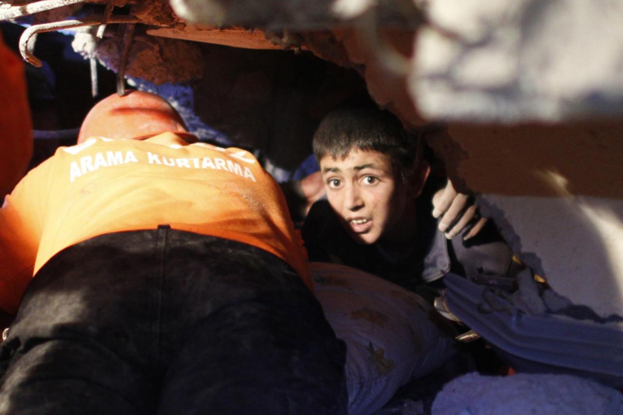 \'Yunus, a 13-year-old earthquake survivor, waits to be rescued from under a collapsed building by rescue workers in Ercis, near the eastern Turkish city of Van, early October 24, 2011. At least 138 p