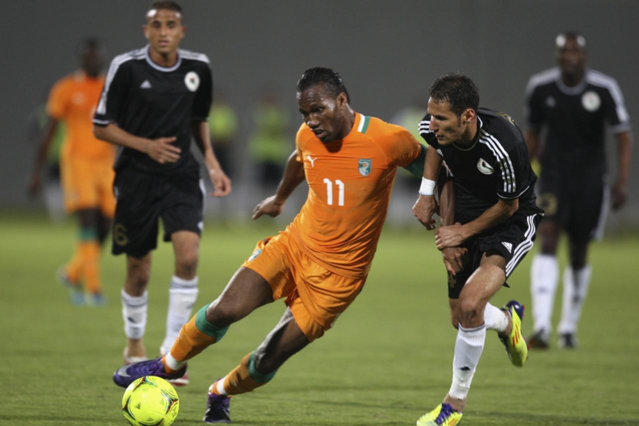 'Ivory Coast\'s striker Didier Drogba (C) fights for the ball with Libya\'s defender Ali Salama during their friendly soccer match in Abu Dhabi January 16, 2012. REUTERS/Rabih El Moghrabi (UNITED ARAB