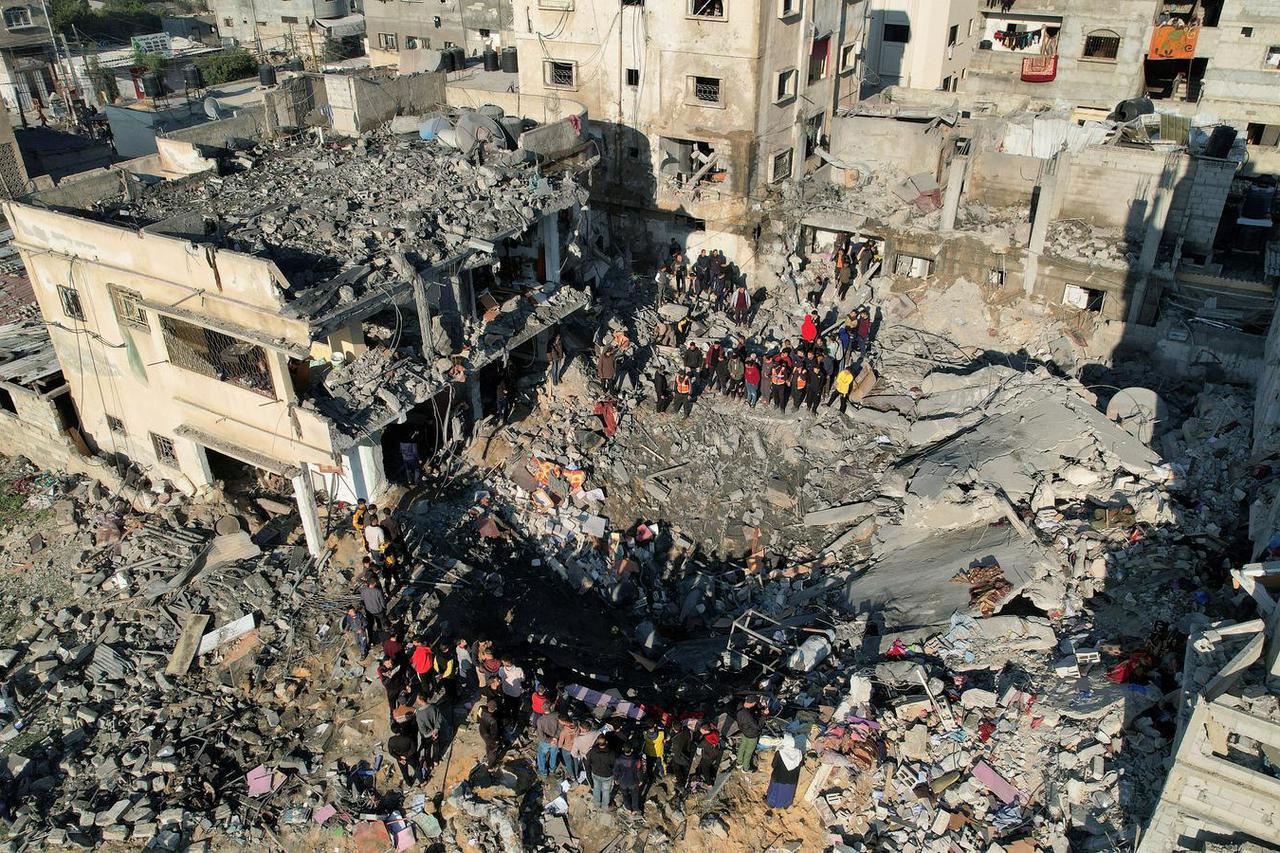 Palestinians gather at the site of an Israeli strike on a house, as the conflict between Israel and Hamas continues, in Rafah