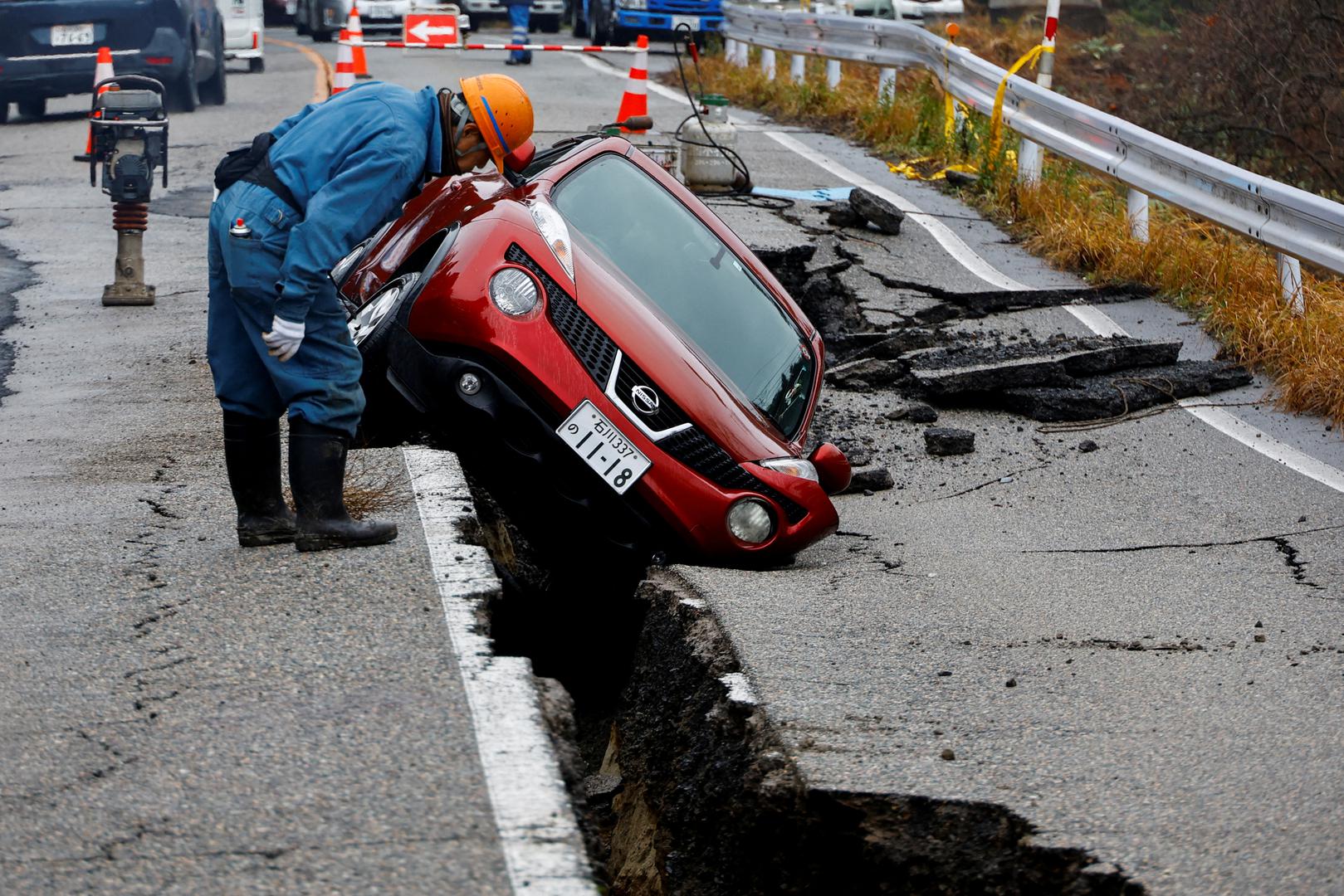 A worker looks at a car stuck on a broken road in the aftermath of an earthquake, near Anamizu, Japan, January 3, 2024. REUTERS/Kim Kyung-Hoon     TPX IMAGES OF THE DAY Photo: KIM KYUNG-HOON/REUTERS
