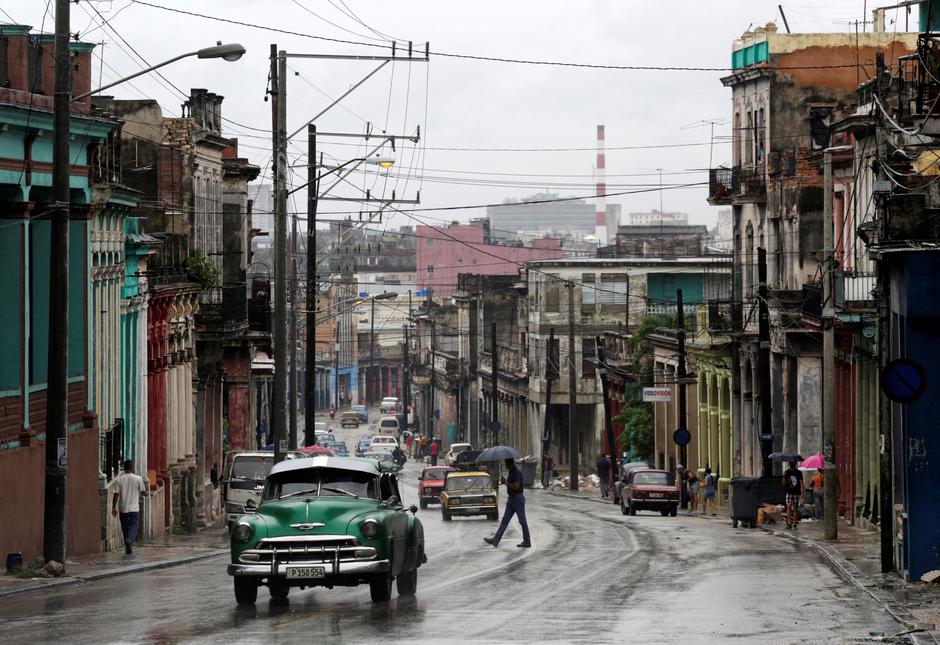 People walk as cars are driven on a street during rain in Havana, Cuba People walk as cars are driven on a street during rain in Havana, Cuba, August 30, 2016. REUTERS/Enrique de la Osa ENRIQUE DE LA OSA
