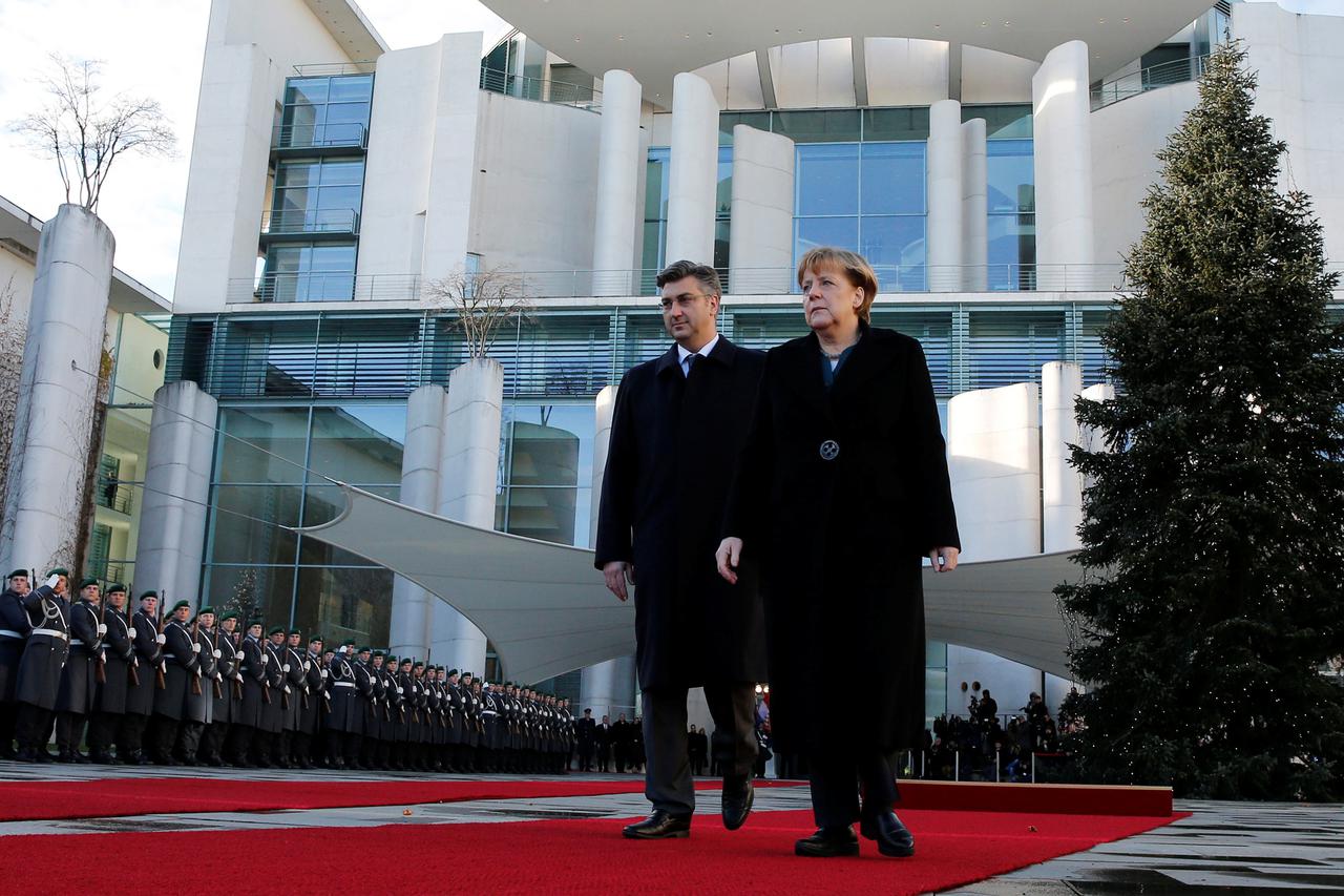 Croatia's Prime Minister Andrej Plenkovic and German Chancellor Angela Merkel review the honor guard during a welcoming ceremony at the chancellery beside a Christmas tree in Berlin, Germany December 12, 2016.  REUTERS/Fabrizio Bensch