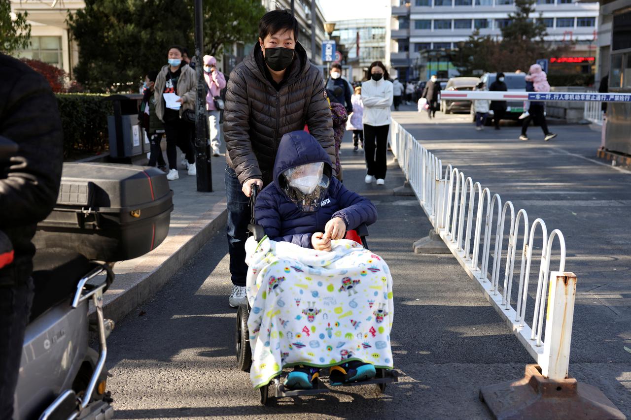 Man pushes a child in a wheelchair outside a children's hospital in Beijing