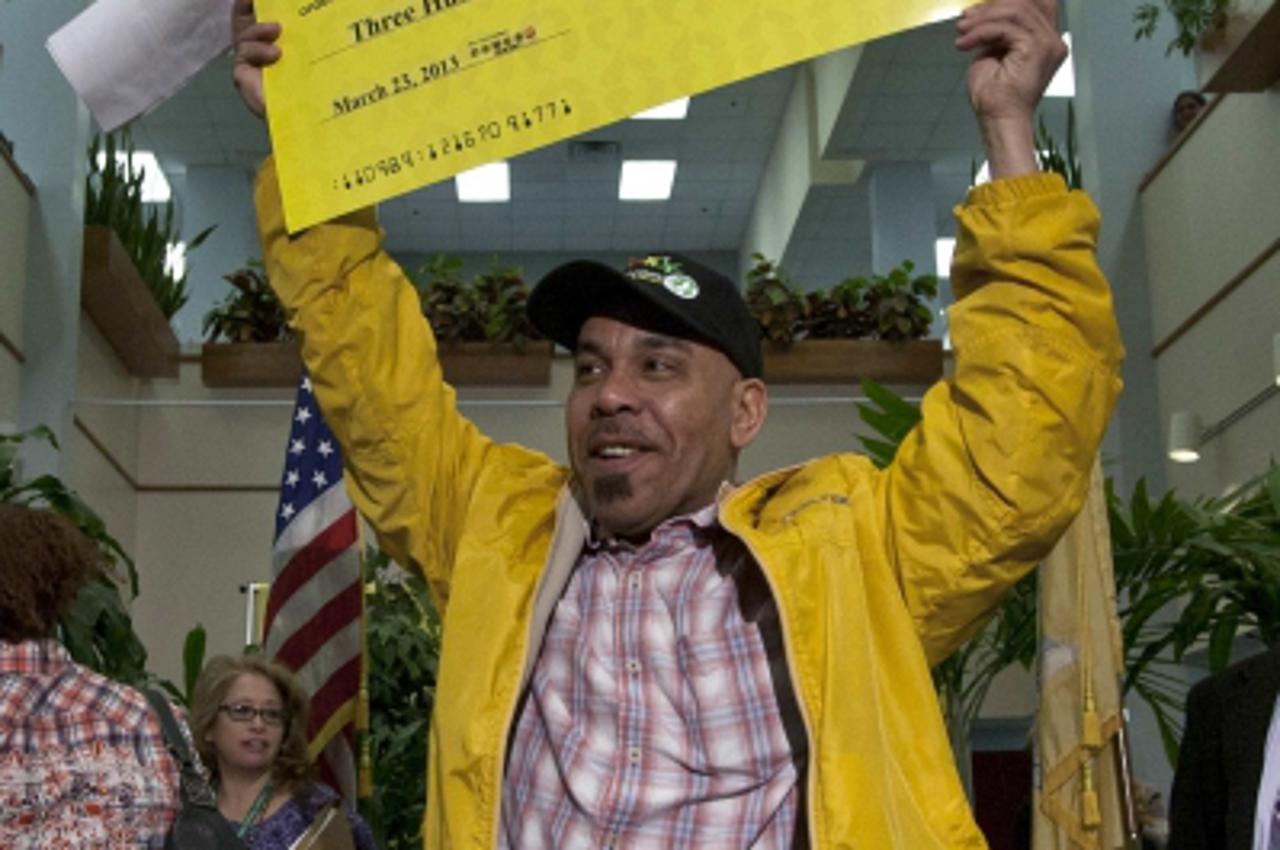 'Pedro Quezada, winner of the Powerball lottery, holds up the promotional Powerball jackpot check of $338 million at the end of a news conference at the New Jersey Lottery headquarters in Trenton, Mar