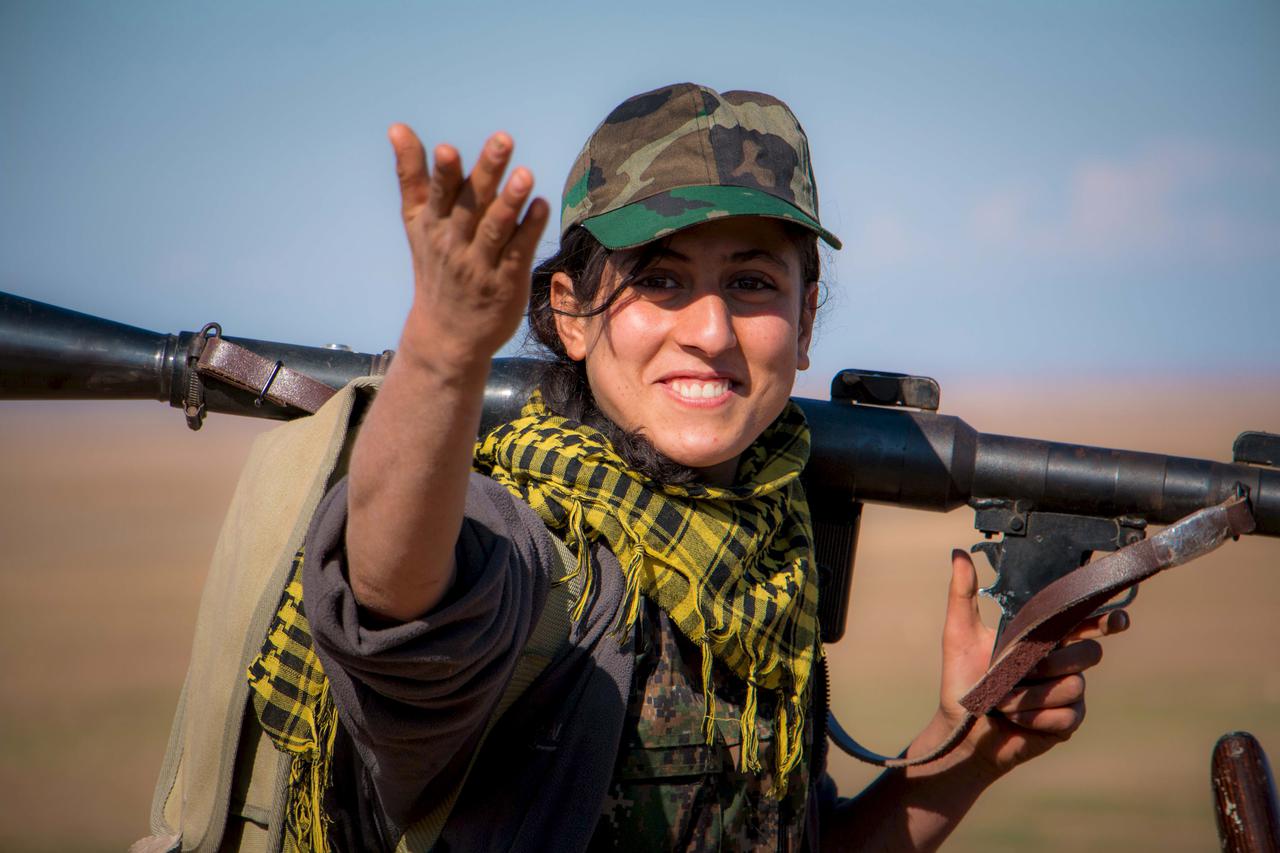 A Kurdish female fighter from the People's Protection Units (YPG) gestures as she carries her weapon near al-Hawl, Syria in this November 10, 2015 file photo. A conference underway in Kurdish-controlled northern Syria aims to approve a 