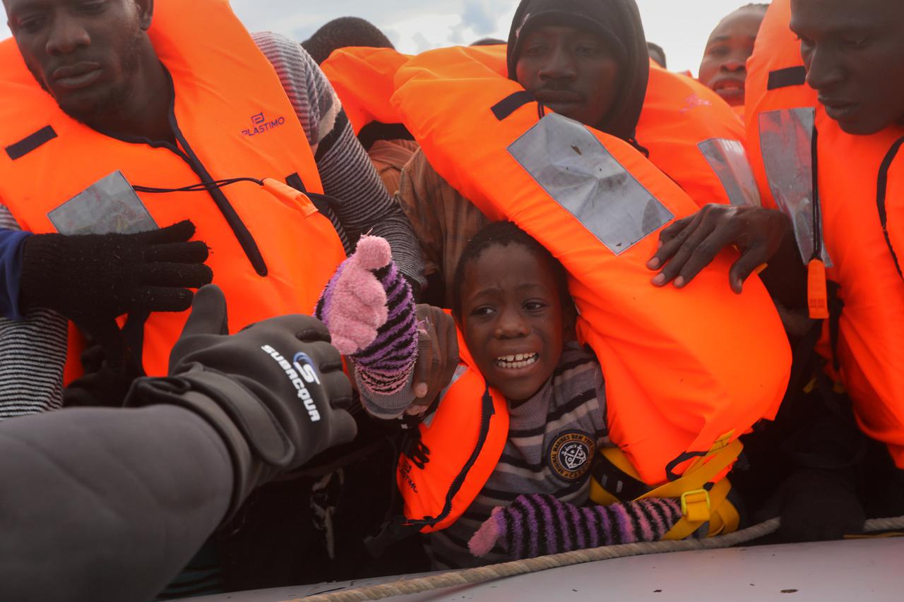 A child reacts among migrants as they try to reach a rescue craft from their overcrowded raft, while lifeguards from the Spanish NGO Proactiva Open Arms rescue all 112 on aboard, including two pregnant women and five children, as it drifts out of control 