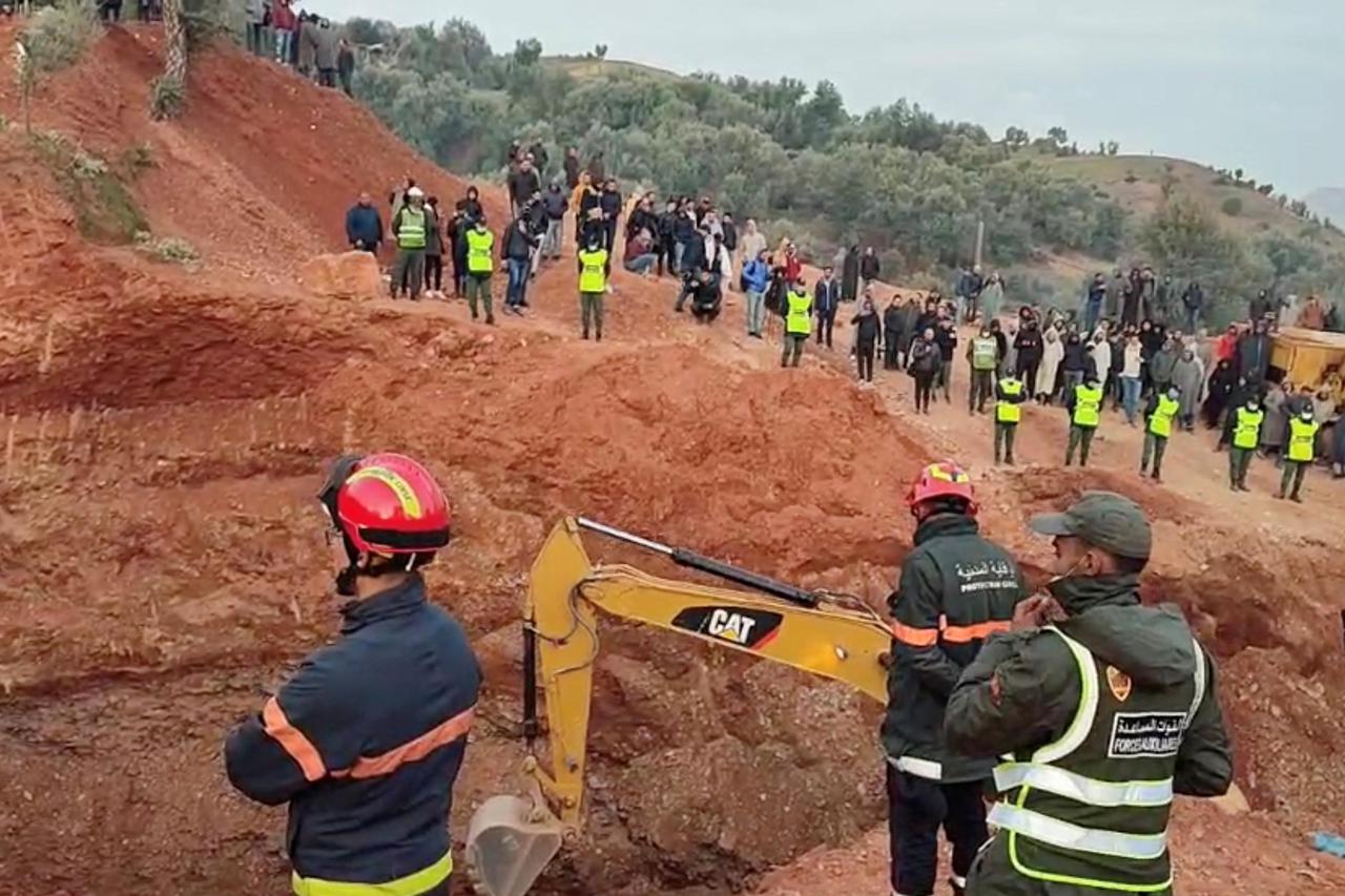 People use machinery to excavate the ground in order to free a boy trapped in an underground well, in Chefchaouen
