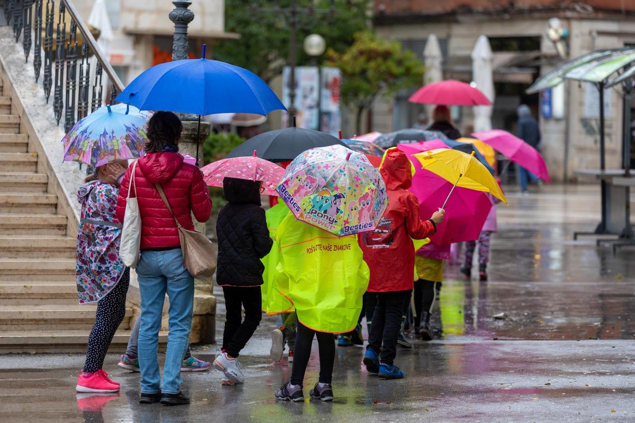 Pula: Školarci zaštićeni kabanicama i kišobranima šeću gradom