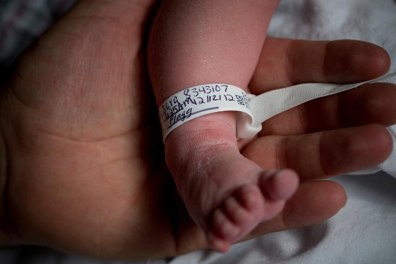 FILE PHOTO: Dale Smith holds the foot of his newborn baby Sofia Murchison-Smith, born at 6:25 am, at the New York Downtown Hospital in New York