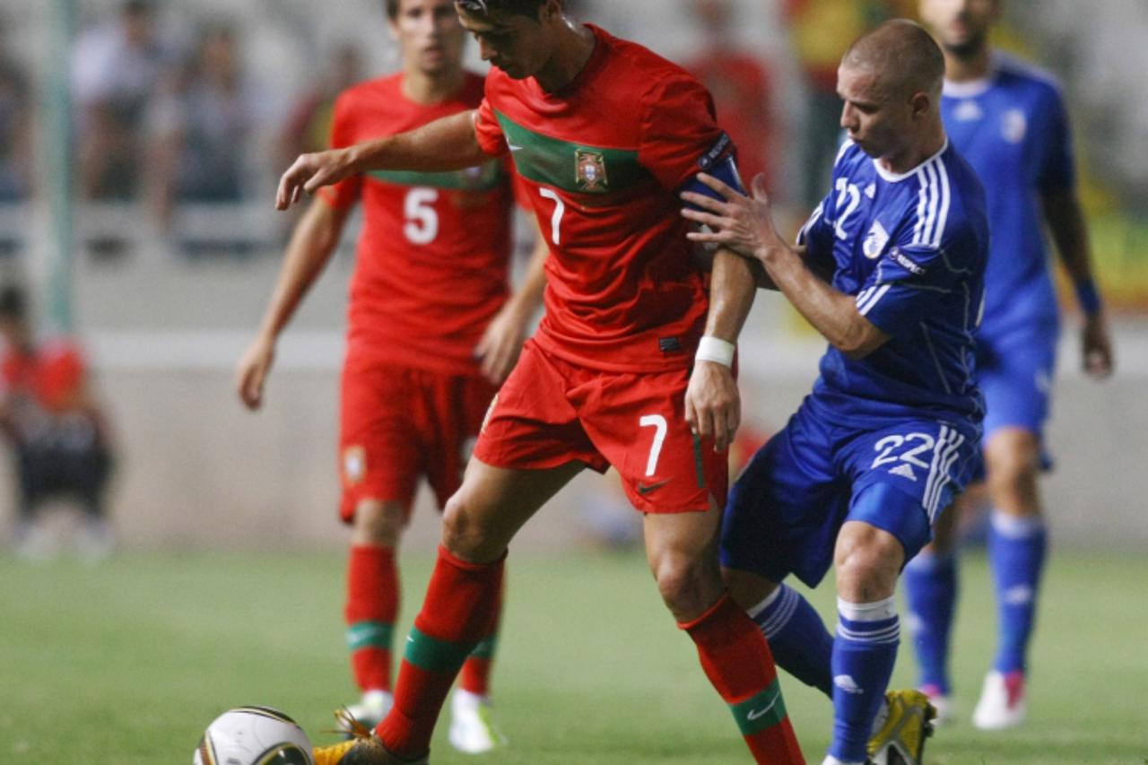 \'Cyprus\' Jason Demetriou (22) vies for the ball against Portugal\'s Cristiano Ronaldo (7) during their Euro 2012 qualifying group H football match in Nicosia on September 2, 2011. AFP PHOTO/SAVIDES 