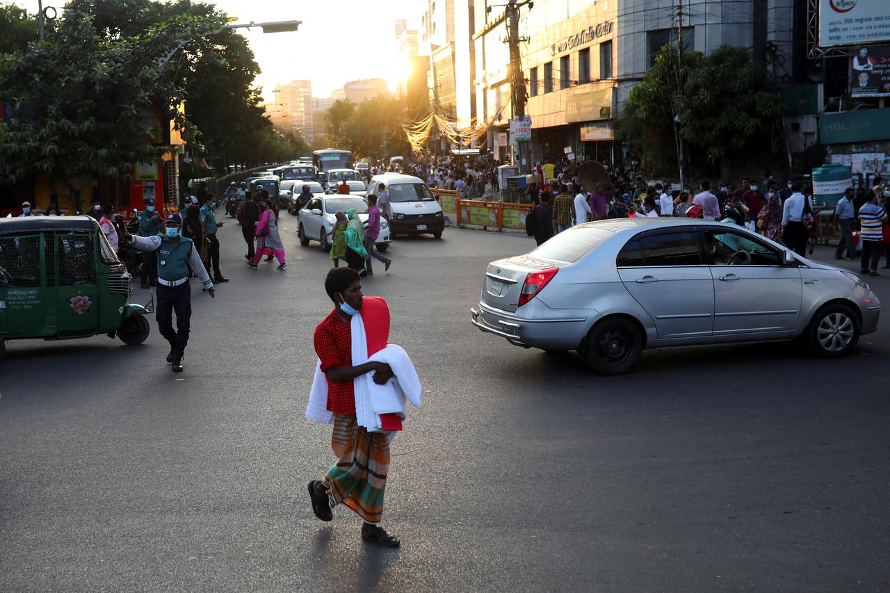 A street vendor crosses a road amid the coronavirus disease (COVID-19) outbreak in Dhaka