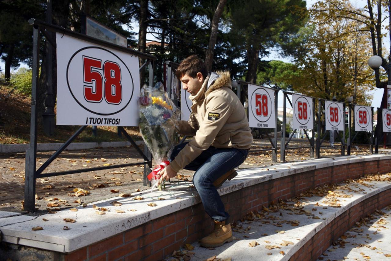 'A fan of Italian rider Marco Simoncelli lays flowers unders his race number in Cattolica on October 23, 2011. Celebrated Italian rider Simoncelli died on after the crash that resulted in the cancella