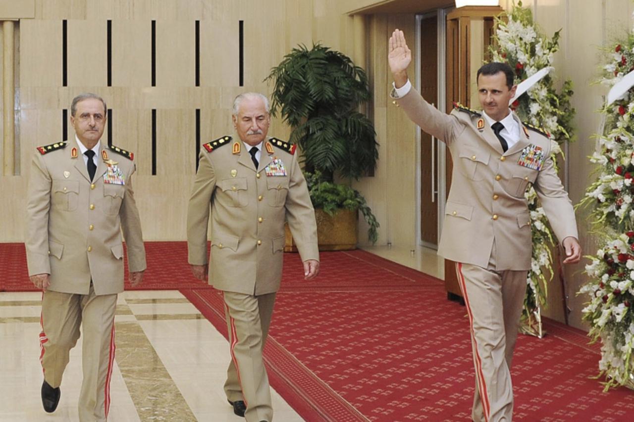 'Syria's President Bashar al-Assad (R) waves as he arrives with Syrian Defense Minister General Ali Habib (C) and Chief of Staff General Dawoud Rajha to attend a dinner to honour army officers on the