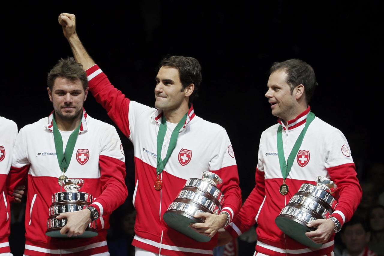 Switzerland's Roger Federer (C) reacts as he stands between Stanislas Wawrinka (L) and Davis Cup tennis team captain Severin Luthi (R) as they pose after winning the Davis Cup tennis tournament final match against France at the Pierre-Mauroy stadium in Vi