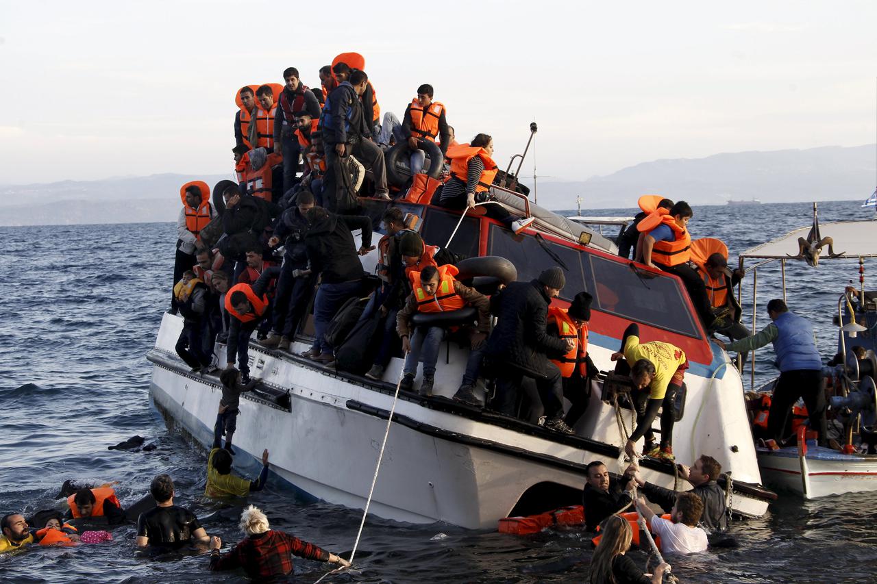 Refugees, most of them Syrians, struggle to leave a half-sunken catamaran carrying around 150 refugees as it arrives on the Greek island of Lesbos, after crossing part of the Aegean sea from Turkey,  October 30, 2015. There were no casaulties amongst the 