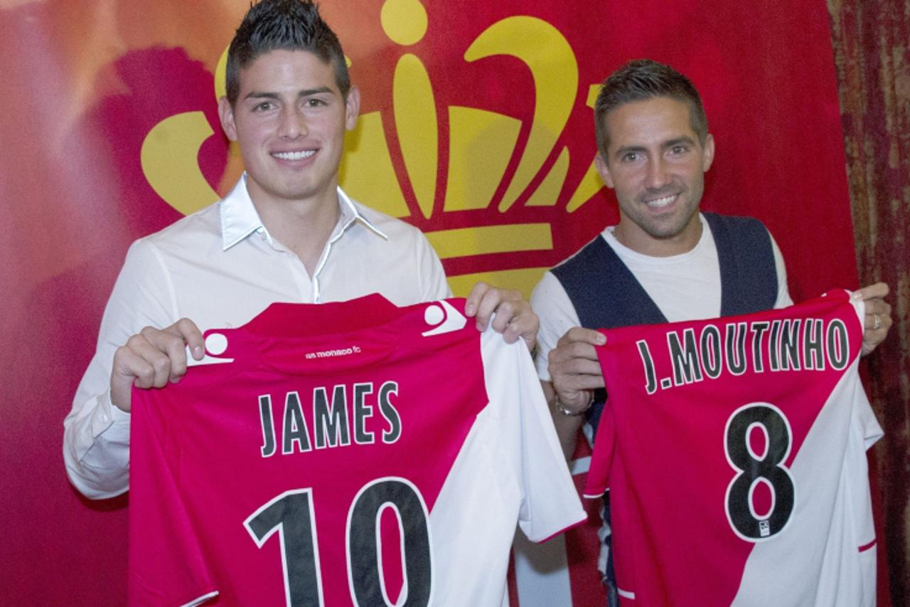 'Soccer players Joao Moutinho (R) of Portugal and James Rodriguez of Colombia, newly-signed players for French Ligue 1 soccer club AS Monaco, hold their jerseys as they pose after a news conference in