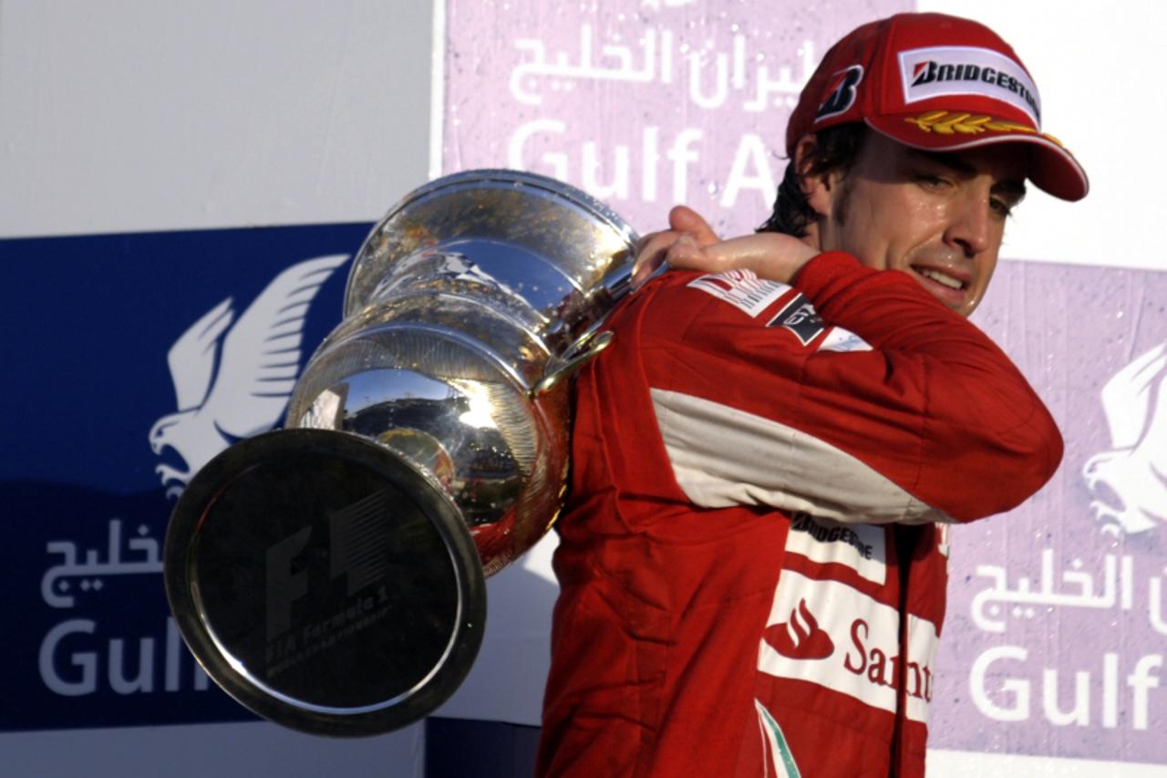 'Ferrari\'s Spanish driver Fernando Alonso leaves the podium with his trophy at the Bahrain international circuit on March 14, 2010 in Manama, after the Bahrain Formula One Grand Prix. Ferrari\'s Span