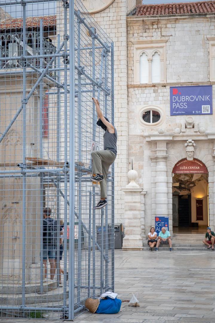 04.09.2022., Orlandov stup, Dubrovnik - Nepoznati ‘performer‘ koji je glavu sakrio popeo se na ogradu kojom je zasticen spomenik Orlando u povijesnoj jezgri Dubrovnika. Muskarac je mirno stajao na ogradi vise od pola sata, nije komunicirao niti je poznato što je svojim postupkom zeli poruciti ili postici. No, na njegov je performas reagirala policija. Dva policajca nisu ga uspjela nagovoriti da se spusti, no uz pojacanje muskarac je spusten s ograde i odvezen u policijskom vozilu.  Photo: Grgo Jelavic/PIXSELL