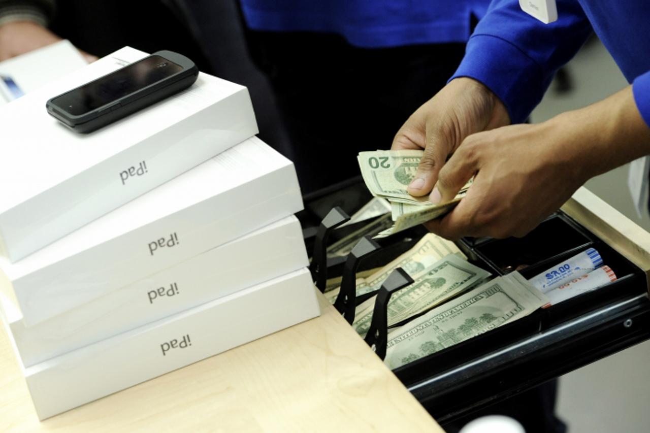 'epa03147435 An Apple employee counts money after a customer bought a new iPad on the first day of availability at an Apple Store in New York, New York, USA, 16 March 2012. This is the third generatio