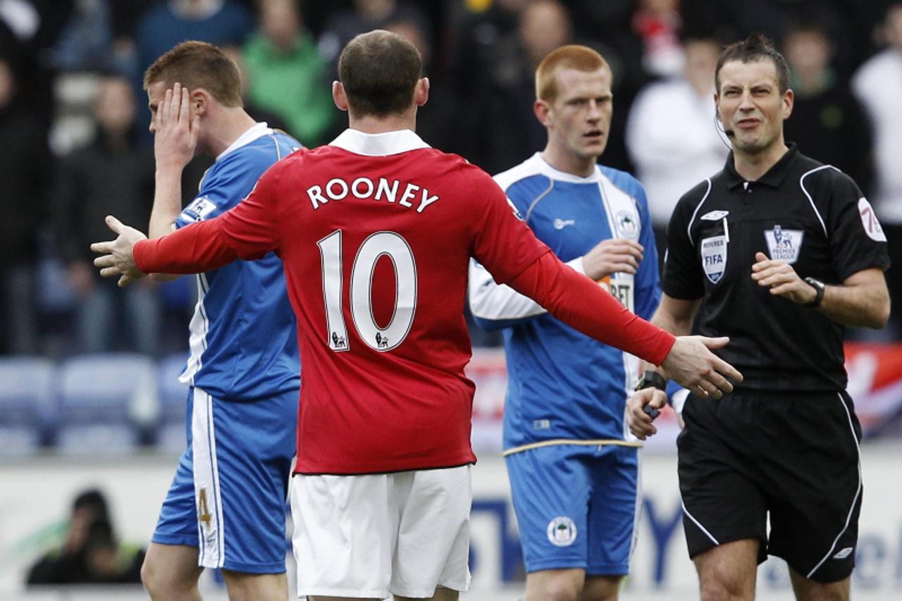 \'REFILE - UPDATING CAPTION Manchester United\'s Wayne Rooney gestures towards referee Mark Clattenburg after clashing with Wigan Athletics\' James McCarthy (L) during their English Premier League soc