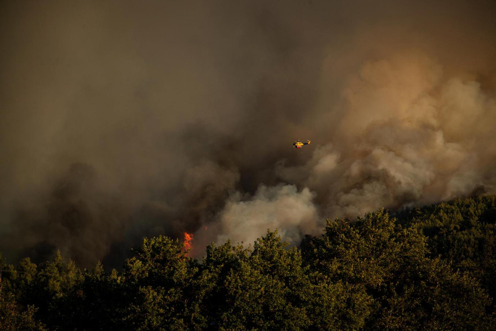 A firefighting helicopter flies over smoke rising from a wildfire in the village of Varnavas, near Athens, Greece, August 11, 2024. REUTERS/Hilary Swift NO RESALES. NO ARCHIVES. Photo: Hilary Swift/REUTERS