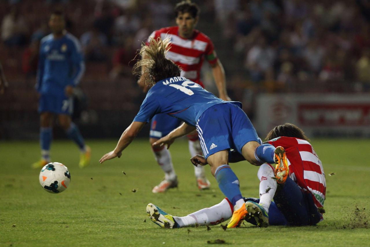 'Real Madrid\'s Luka Modric (L) falls in the penalty area next to Granada\'s Pape Diakhate during their Spanish first division soccer match at Los Carmenes stadium in Granada August 26, 2013. REUTERS/