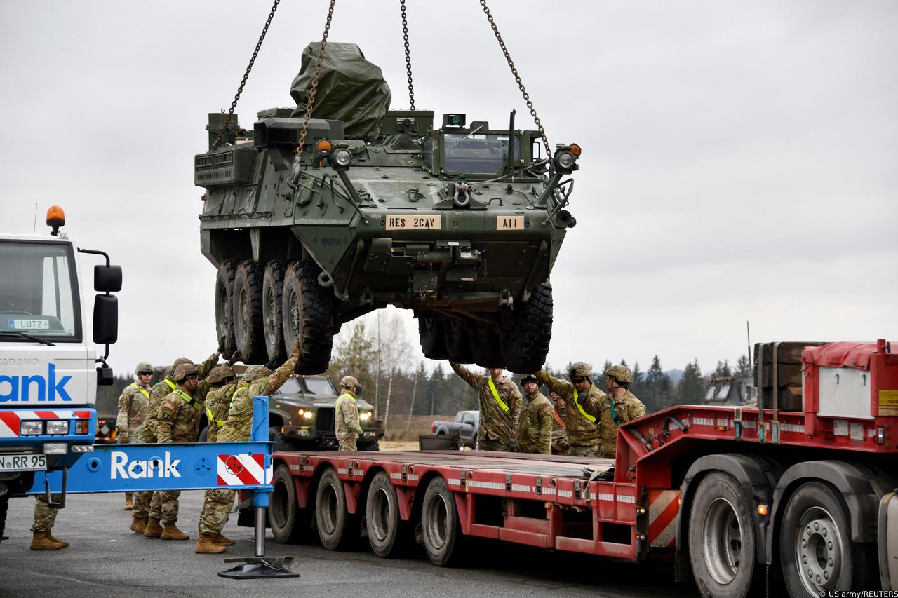 U.S. Army soldiers load a Stryker armored vehicle onto a truck at Rose Barracks Air Field