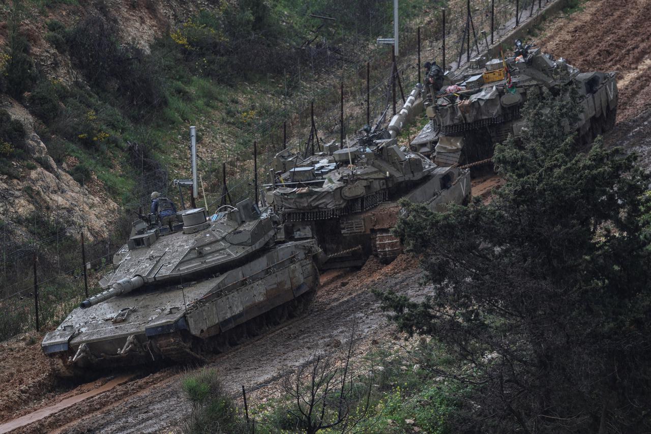Israeli soldiers lean out from a tank to inspect a disabled tank stuck in the mud, on the Israeli side of the border with Lebanon, amid escalation between Iran-backed Hezbollah and Israel and the U.S.-Israeli conflict with Iran