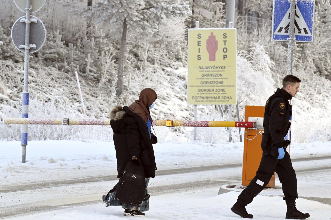 Migrants walk at the border crossing between Finland and Russia, in Finnish Lapland