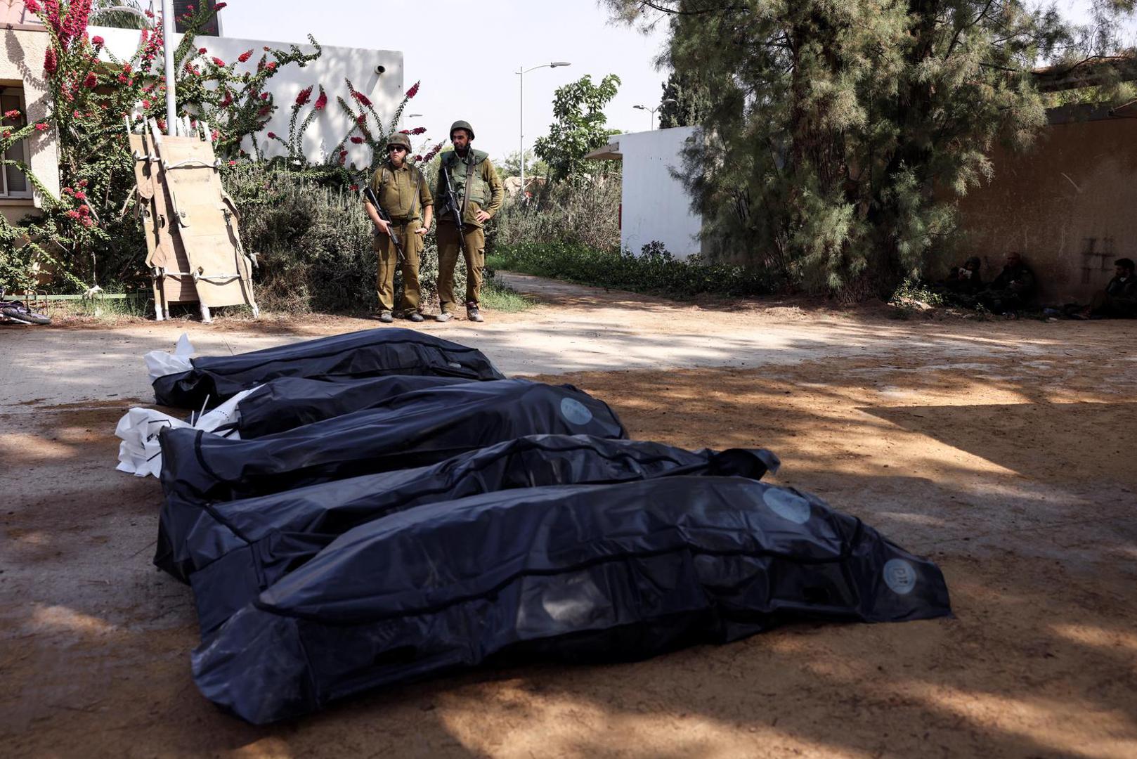 Israeli soldiers guard the bodies of victims of an attack following a mass infiltration by Hamas gunmen from the Gaza Strip, in Kibbutz Kfar Aza, in southern Israel, October 10, 2023. REUTERS/Ronen Zvulun Photo: RONEN ZVULUN/REUTERS
