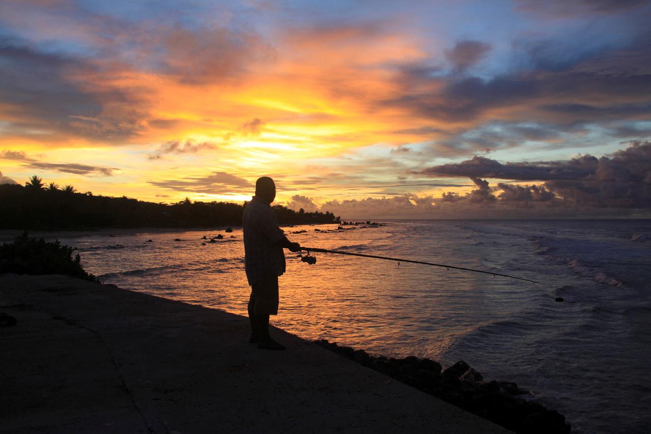 FILE PHOTO: A fisherman is pictured at sunset at the northern end of the airport runway on the nation island of Nauru