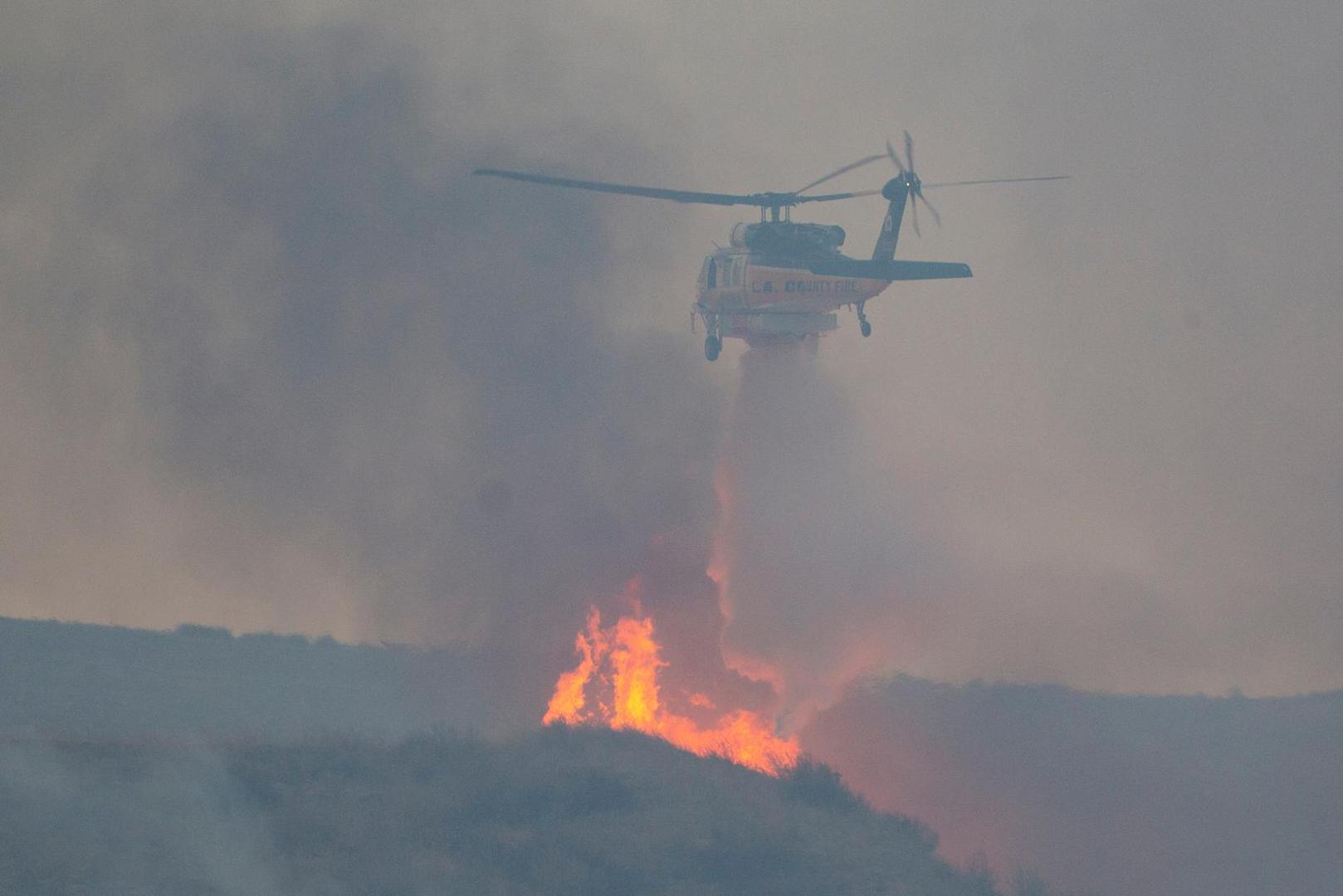 A helicopter drops water, as firefighters and aircraft battle the Hughes Fire near Castaic Lake, north of Santa Clarita, California, U.S. January 22, 2025.  REUTERS/Ringo Chiu Photo: RINGO CHIU/REUTERS