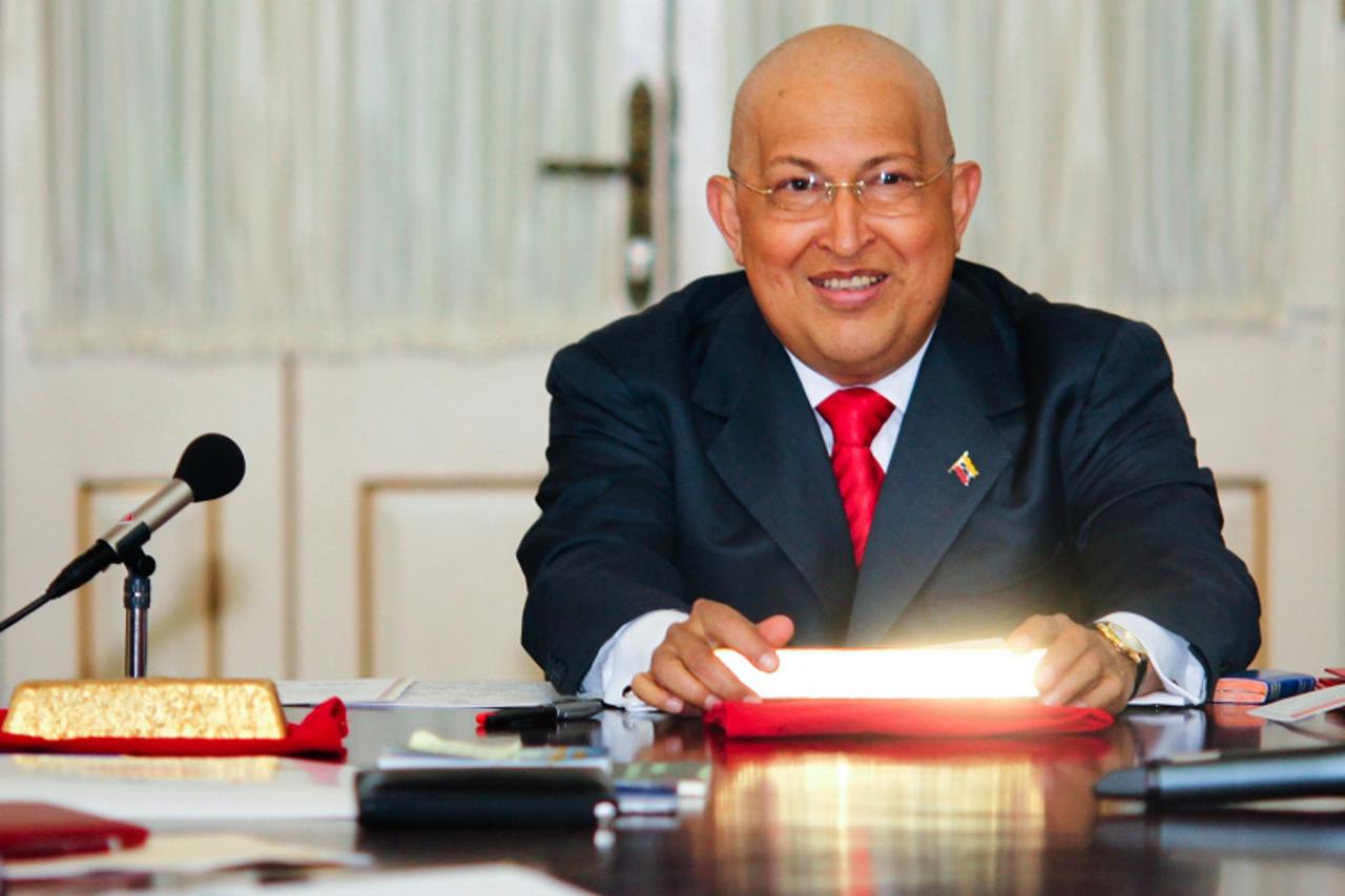 'Venezuela\'s President Hugo Chavez smiles while holding a gold ingot after signing a decree for the nationalization of the gold mining industry, at Miraflores Palace in Caracas August 23, 2011.  REUT